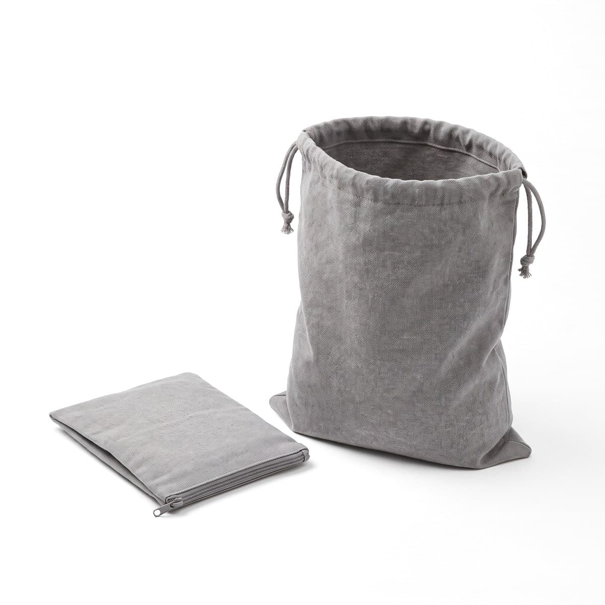 A grey drawstring laundry bag standing open with the word Laundry printed on the front, beside the flat pouch it folds into