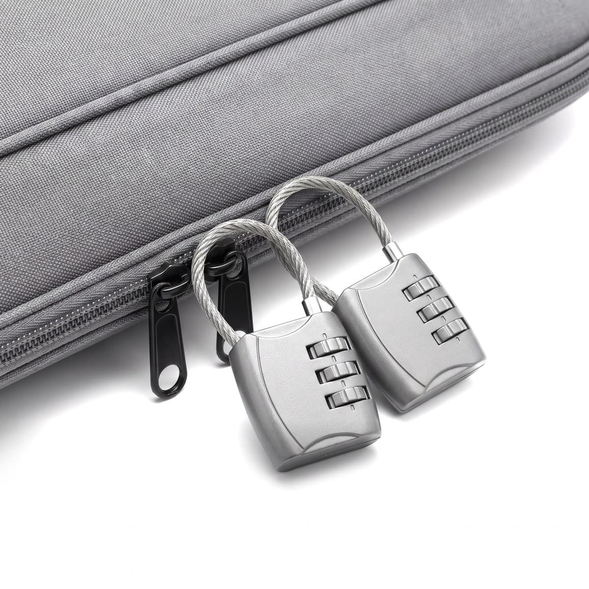 Two grey three-dial combination luggage locks with braided steel cable shackles, one shackle threaded through two zip pulls
